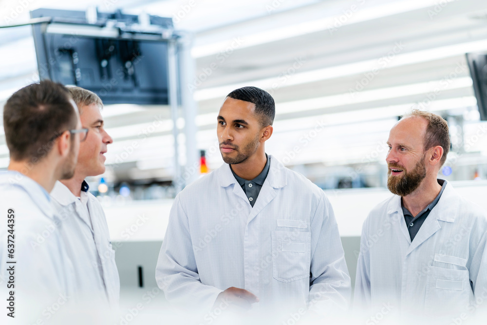 Technicians in lab coats discussing in electronics factory Technicians in lab coats discussing in electronics factory