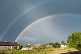 Double rainbow on the background of rainy sky over the village