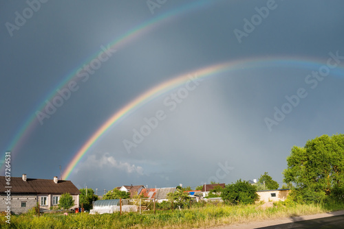 Double rainbow on the background of rainy sky over the village © kulkann