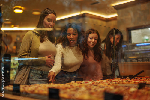 Girl pointing to a pizza slice showing it to her friends