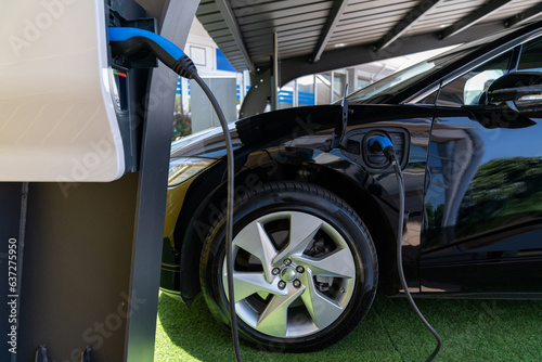 Electric car is charged from a charging station that takes energy from solar panels. Close up