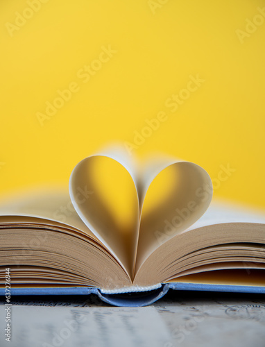 Heart from a book page on yellow background, book of love