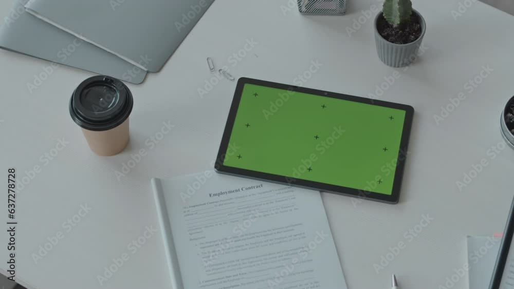 No people top view shot of digital tablet with green template screen and printed business contract on white office desk