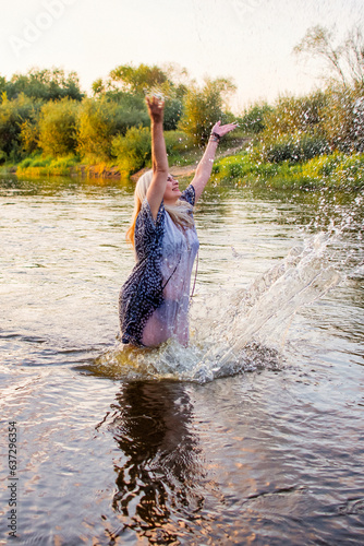 beautiful cheerful woman in the river with water splashes