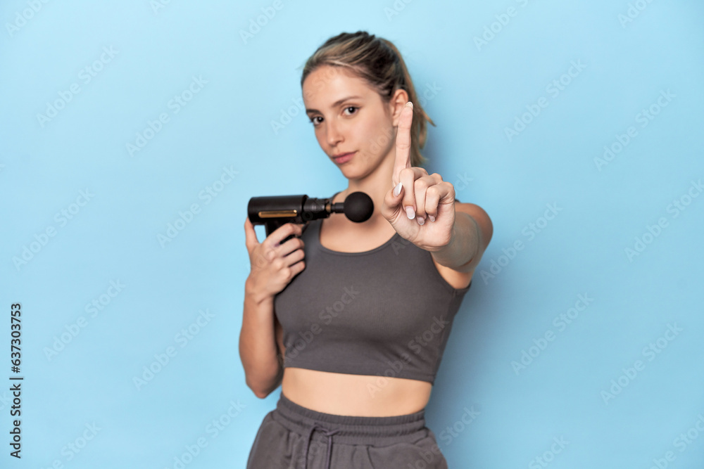 Athlete holding an electric massager showing number one with finger. Athlete holding an electric massager showing number one with finger.