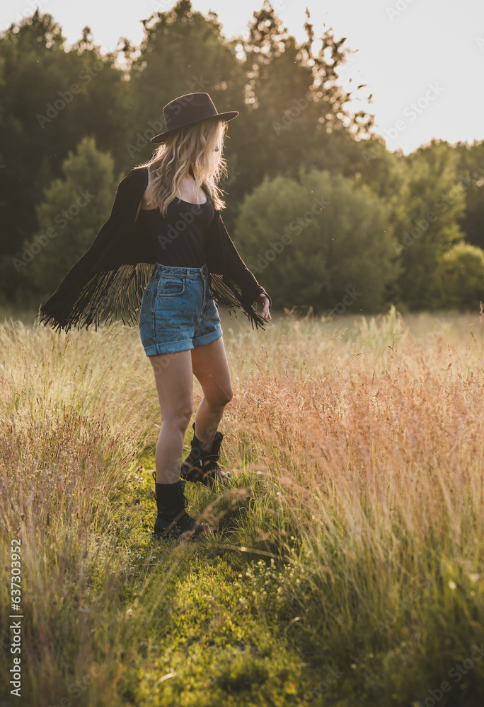 American cowgirl in country style. Nice young woman stylishly dressed at field