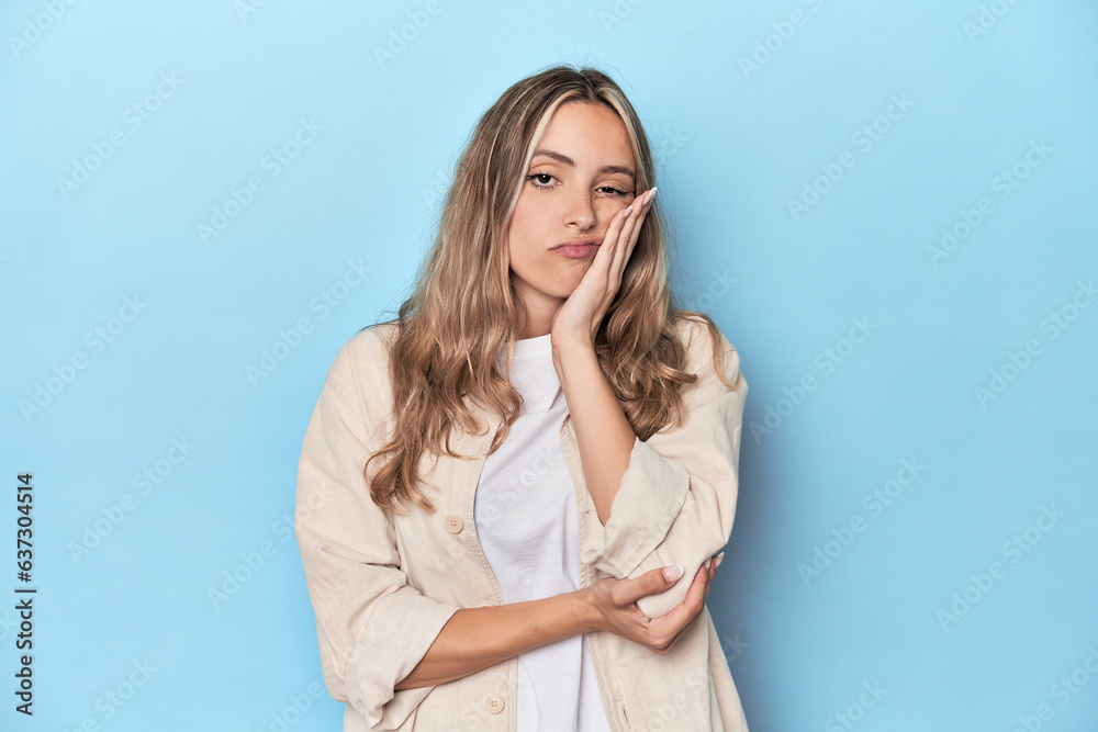 Blonde young caucasian woman in blue studio who is bored, fatigued and need a relax day. Blonde young caucasian woman in blue studio who is bored, fatigued and need a relax day.