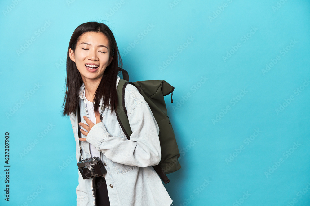 Young Asian traveler ready to capture adventures, laughs out loudly keeping hand on chest. Young Asian traveler ready to capture adventures, laughs out loudly keeping hand on chest.