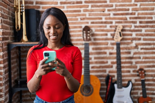 Canvas Print Young african american woman musician smiling confident using smartphone at musi