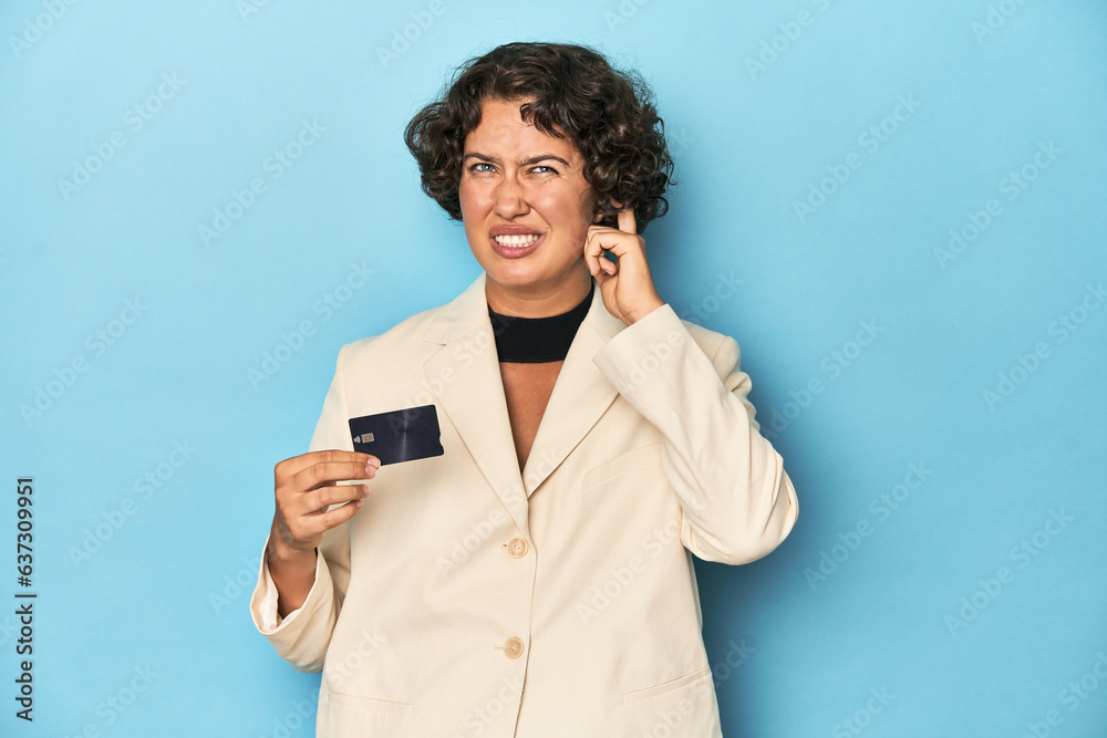 Young woman with credit card, elegant white blazer covering ears with hands. Young woman with credit card, elegant white blazer covering ears with hands.
