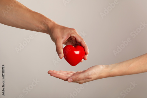 Red heart in arms on a gray background. Blood donation photo