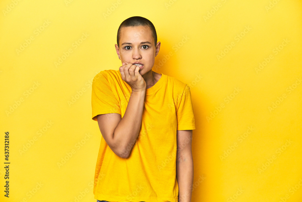 Young woman in yellow tee, yellow studio backdrop biting fingernails, nervous and very anxious. Young woman in yellow tee, yellow studio backdrop biting fingernails, nervous and very anxious.