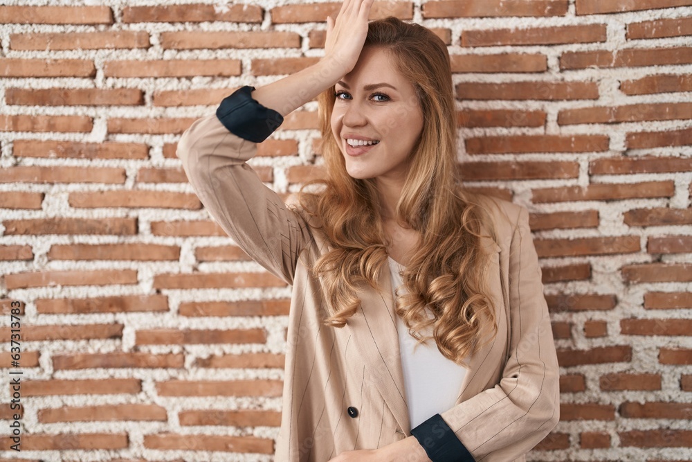 Beautiful blonde woman standing over bricks wall surprised with hand on head for mistake, remember error. forgot, bad memory concept. Beautiful blonde woman standing over bricks wall surprised with hand on head for mistake, remember error. forgot, bad memory concept.