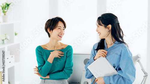 Bild auf Leinwand オフィスでノートパソコンを見ながら話す二人の女性
