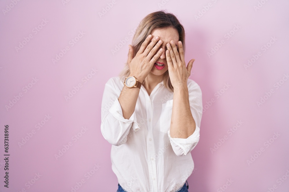 Young beautiful woman standing over pink background rubbing eyes for fatigue and headache, sleepy and tired expression. vision problem Young beautiful woman standing over pink background rubbing eyes for fatigue and headache, sleepy and tired expression. vision problem