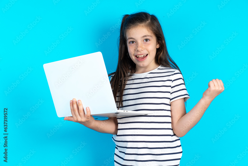 Caucasian kid girl wearing floral dress over blue background directing empty space hold laptop Caucasian kid girl wearing floral dress over blue background directing empty space hold laptop