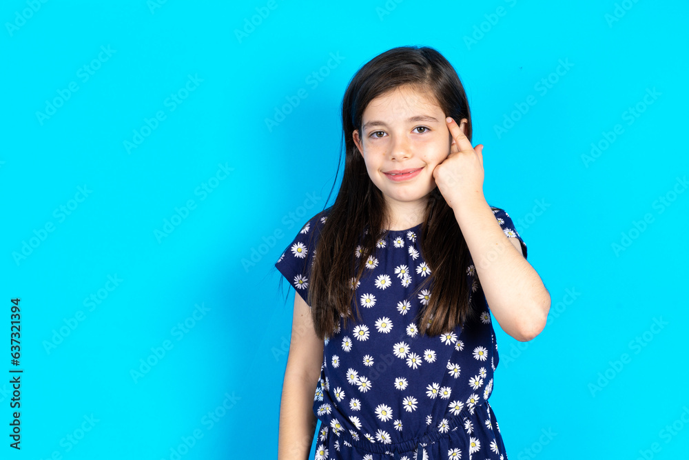 Caucasian kid girl wearing floral dress over blue background looking confident at the camera smiling with crossed arms and hand raised on chin. Thinking positive. Caucasian kid girl wearing floral dress over blue background looking confident at the camera smiling with crossed arms and hand raised on chin. Thinking positive.