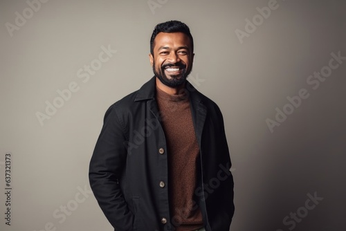Medium shot portrait of an Indian man in his 30s in a minimalist background