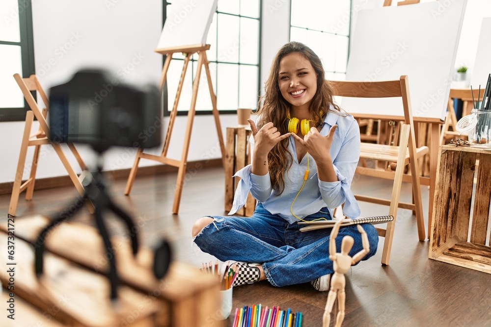 Young beautiful hispanic woman artist recording draw lesson communicate with deaf language at art studio