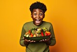 Surprise African Boy Holds And Eats Grilled Vegetables On Pastel Background. Сoncept Surprise, African Boy, Grilled Vegetables, Pastel Background