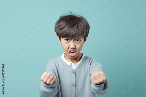 Anger Asian Boy In A Gray Cardigan On Pastel Background. Сoncept Exploring Anger, Asian Representation, Gray Cardigan, Pastel Background photo