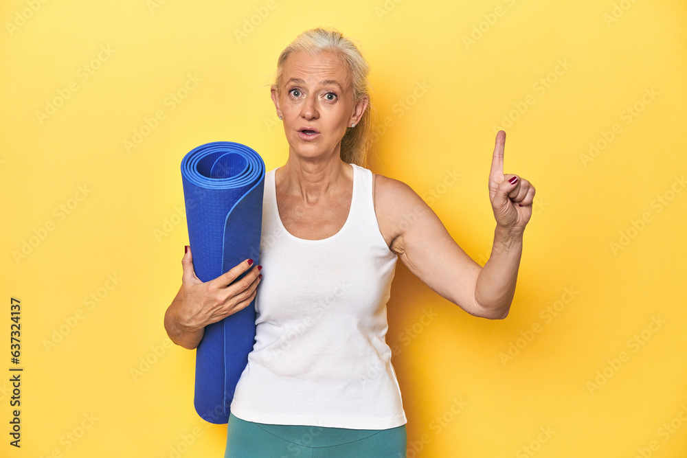 Fitness woman with yoga mat, sportswear on yellow backdrop having some great idea, concept of creativity. Fitness woman with yoga mat, sportswear on yellow backdrop having some great idea, concept of creativity.