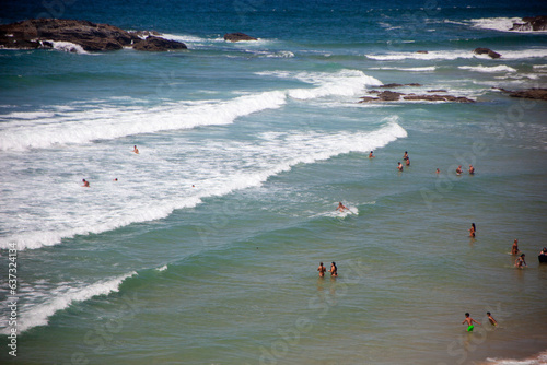 Vibrant scene at Porto Covo's expansive beach: bathers enjoying the waves, basking in the sun, and playing in the sea's embrace.