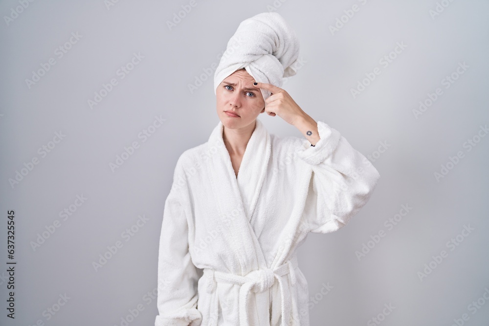 Blonde caucasian woman wearing bathrobe pointing unhappy to pimple on forehead, ugly infection of blackhead. acne and skin problem Blonde caucasian woman wearing bathrobe pointing unhappy to pimple on forehead, ugly infection of blackhead. acne and skin problem