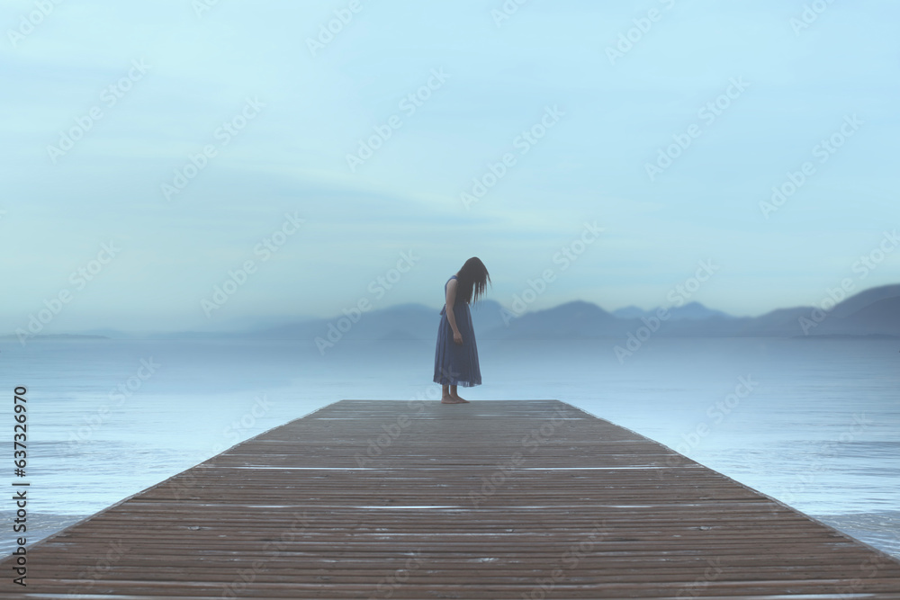 lonely woman standing on a pier by the sea gets carried away by emotions in a blue surreal atmosphere - obrazy, fototapety, plakaty 