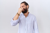 Hispanic man with beard wearing casual shirt smelling something stinky and disgusting, intolerable smell, holding breath with fingers on nose. bad smell