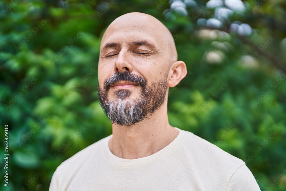 Young bald man breathing with closed eyes at park Young bald man breathing with closed eyes at park