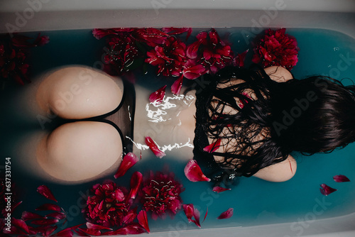 young girl with a sexy ass in beautiful underwear lies in a bath with peony flowers