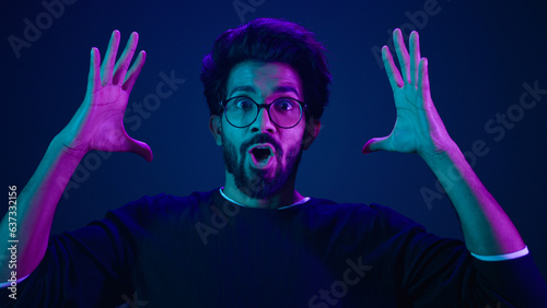 Male portrait neon ultraviolet background Arabian man Indian guy coder hacker showing head mind explosion gesture boom brainstorm idea mental shock information think computer technology sci-fi future
