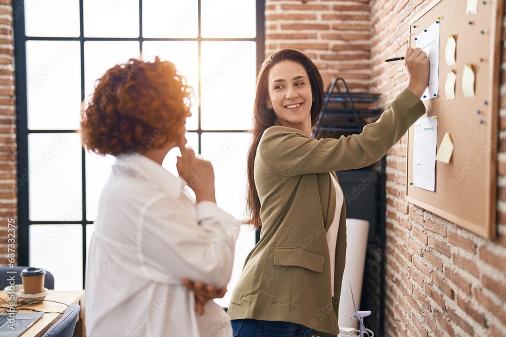 Obraz premium Two women business workers writing on cork board at office