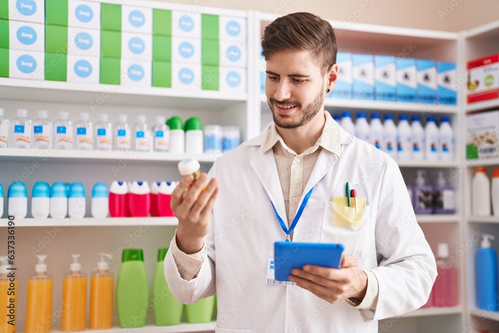 Young caucasian man pharmacist using touchpad holding pills at pharmacy