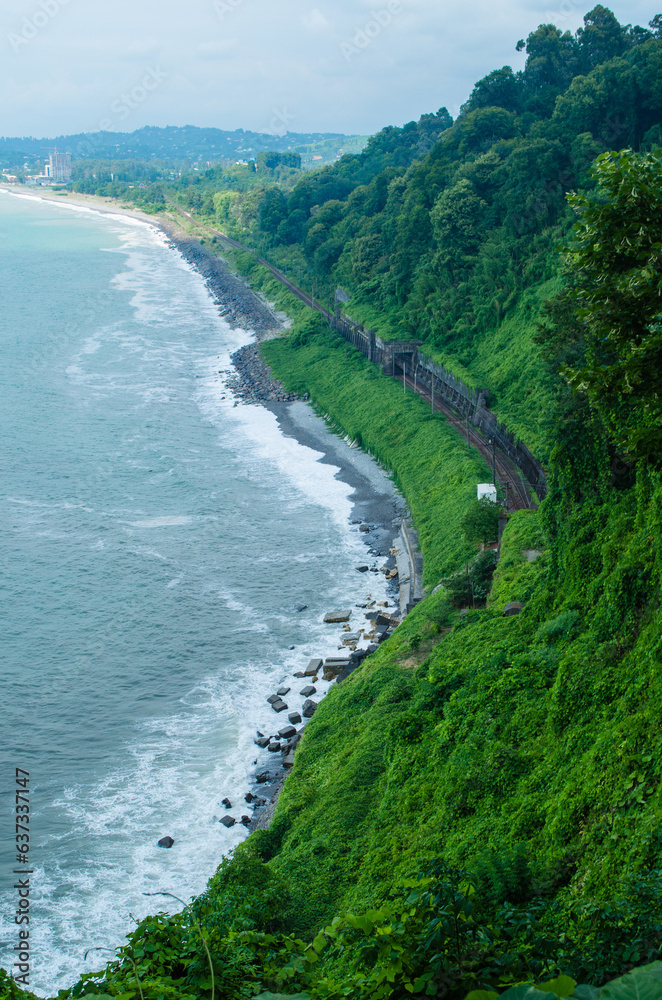 Seaside landscape nature photography with green hills and railroad. Batumi botanical garden. Sceneric view with bright vivid green, the sea and the stony shore. Travel photography, Georgia. Tourist