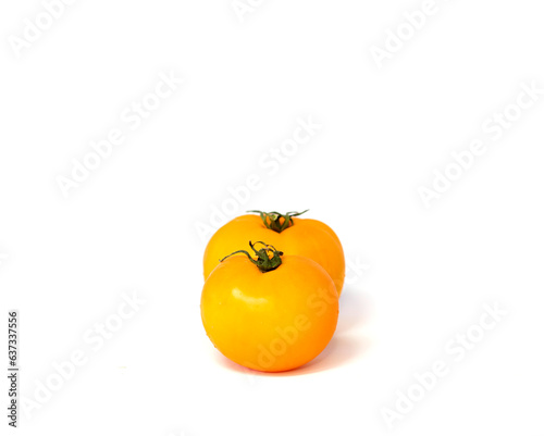 Two vibrant yellow tomatoes isolated on white background.