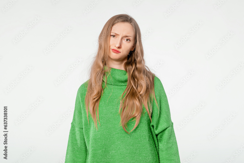 Irritated dissatisfied blonde woman wears green cozy sweater, looking camera, posing on white background. People emotions lifestyle concept Irritated dissatisfied blonde woman wears green cozy sweater, looking camera, posing on white background. People emotions lifestyle concept