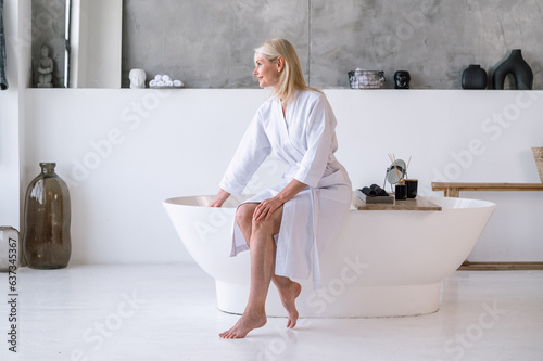 Woman sitting at bath, waiting until water fill the bathtub
