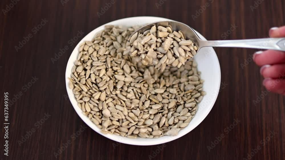 Sunflower kernels in a white bowl on a wooden table. Sunflower kernels in a white bowl on a wooden table.