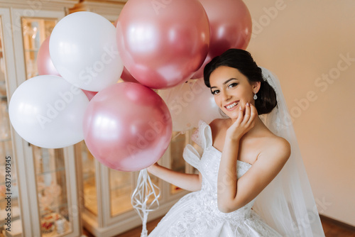 young girl bride in luxury room in white wedding dress holding many gel balloons and preparing for wedding ceremony