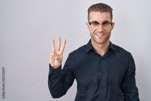 Young caucasian man standing over isolated background showing and pointing up with fingers number three while smiling confident and happy.