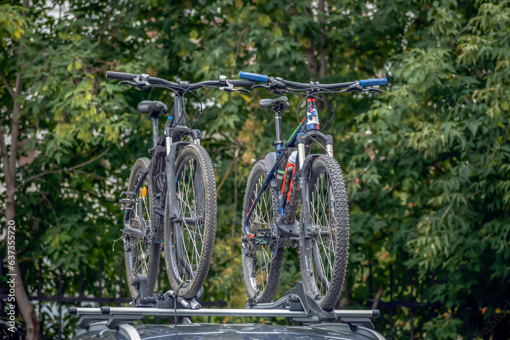 Mountain bikes are mounted on the trunk of a car on a summer day Mountain bikes are mounted on the trunk of a car on a summer day