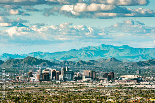 The skyscrapers of Phoenix, Arizona against mountains and a cloud-filled sky.
