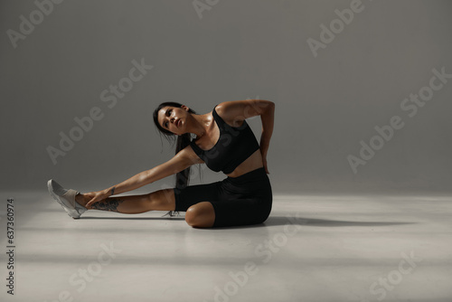 close-up. Fitness woman relaxing after workout sitting on the floor in the gym. stretching Mockup of leggings is done. Tan. sun in the studio