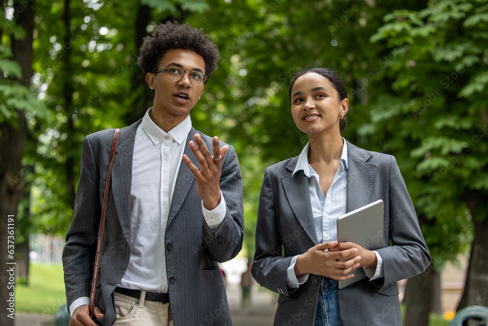 Colleagues walking in the park during the break and discussing business issues