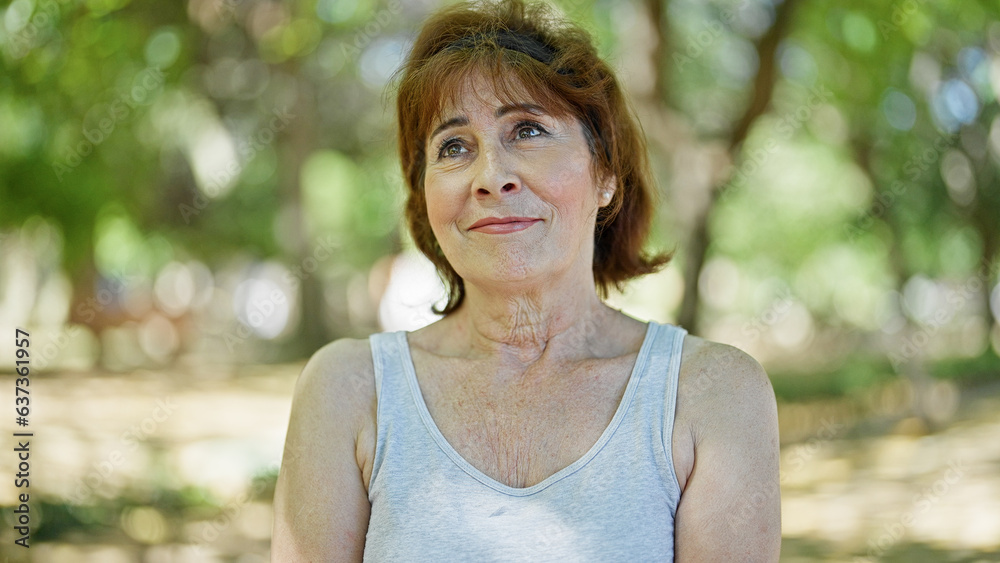 Middle age woman looking to the side smiling at park Middle age woman looking to the side smiling at park