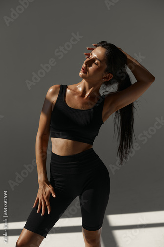 close-up. Fitness woman relaxing after workout sitting on the floor in the gym. stretching Mockup of leggings is done. Tan. sun in the studio
