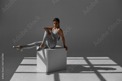 The girl performs exercises in the gym in the morning sun. Photo of a tanned girl in sportswear isolated on white. Strength and motivation