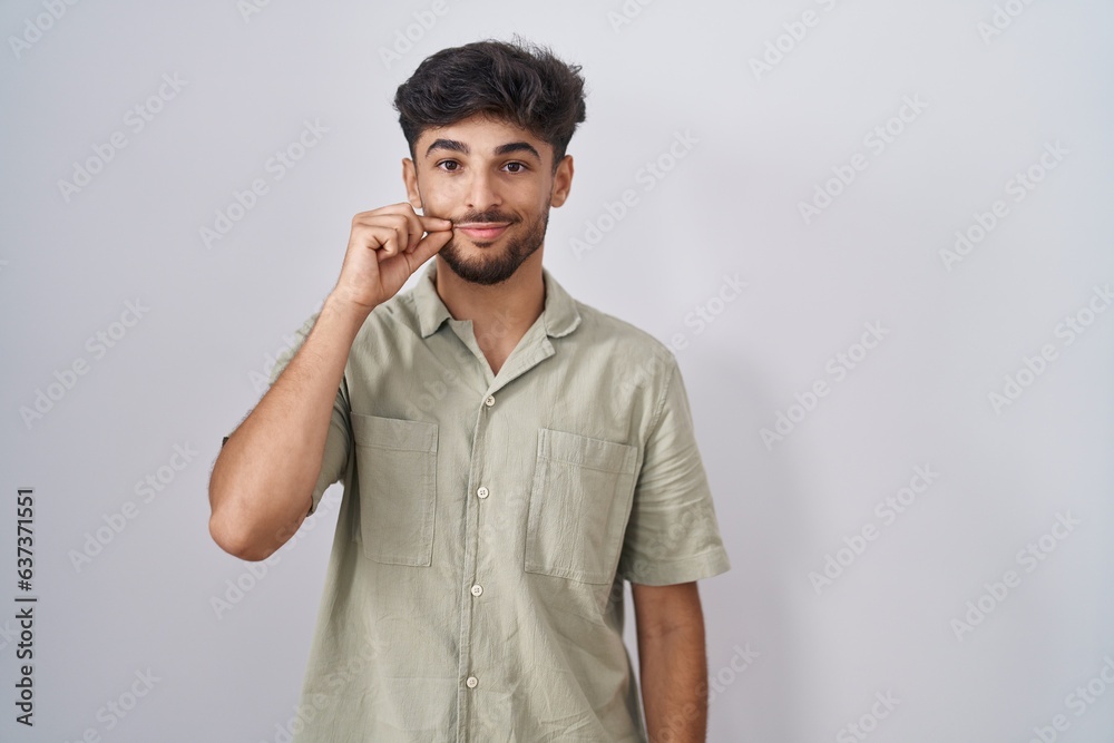 Arab man with beard standing over white background mouth and lips shut as zip with fingers. secret and silent, taboo talking Arab man with beard standing over white background mouth and lips shut as zip with fingers. secret and silent, taboo talking